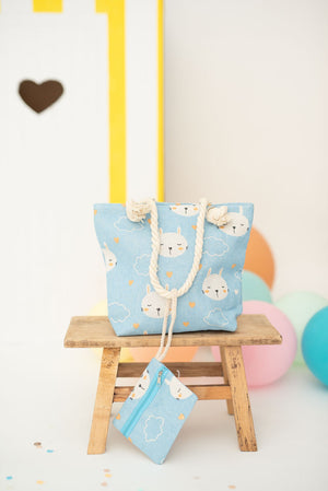 Blue tote bag with cat patterns on a wooden stool against a colorful background