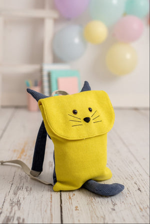 Yellow backpack with cat design on a wooden floor with colorful balloons in the background