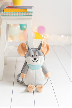 Dog backpack on a white wooden floor with colorful balloons in the background.