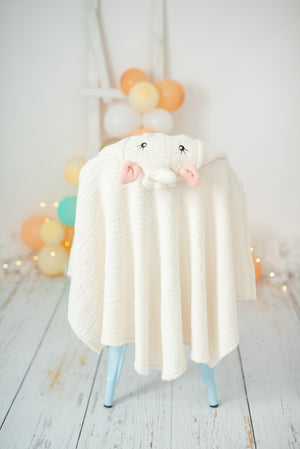 White unicorn hooded towel hanging on a white chair against a light background with colorful balloons.